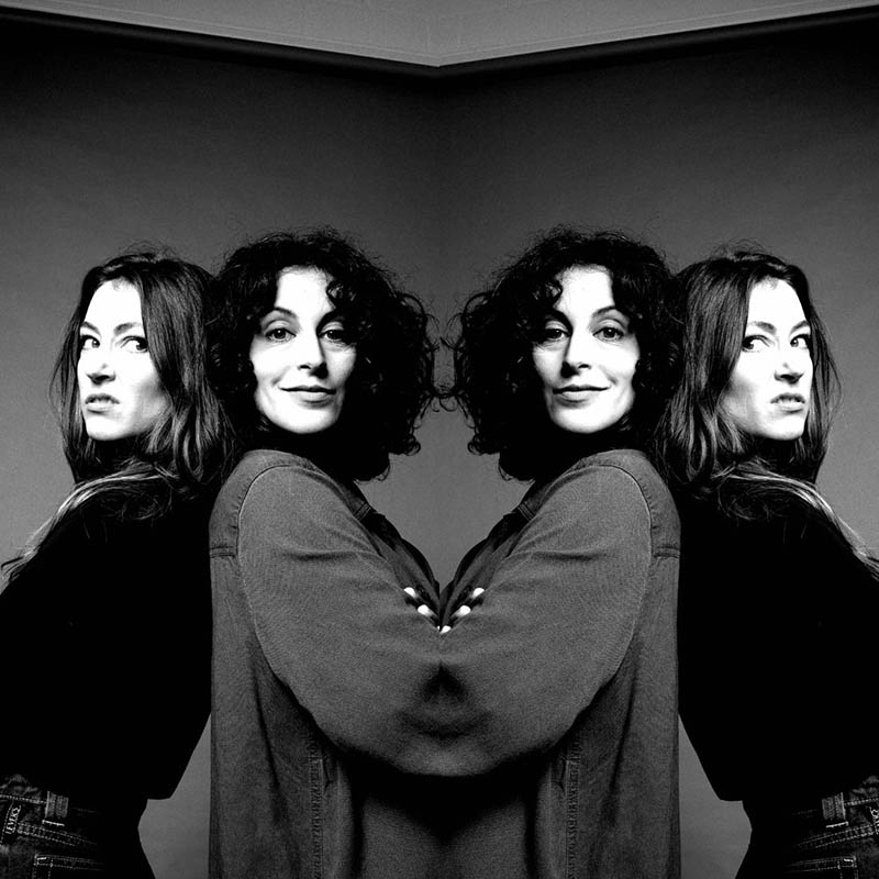 Black and white mirror image of Roisin and Chiara stood back to back