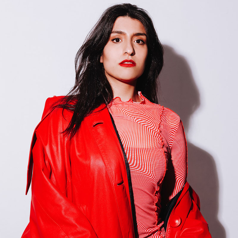 Photo of Celya AB wearing a red jacket, slipping off one shoulder