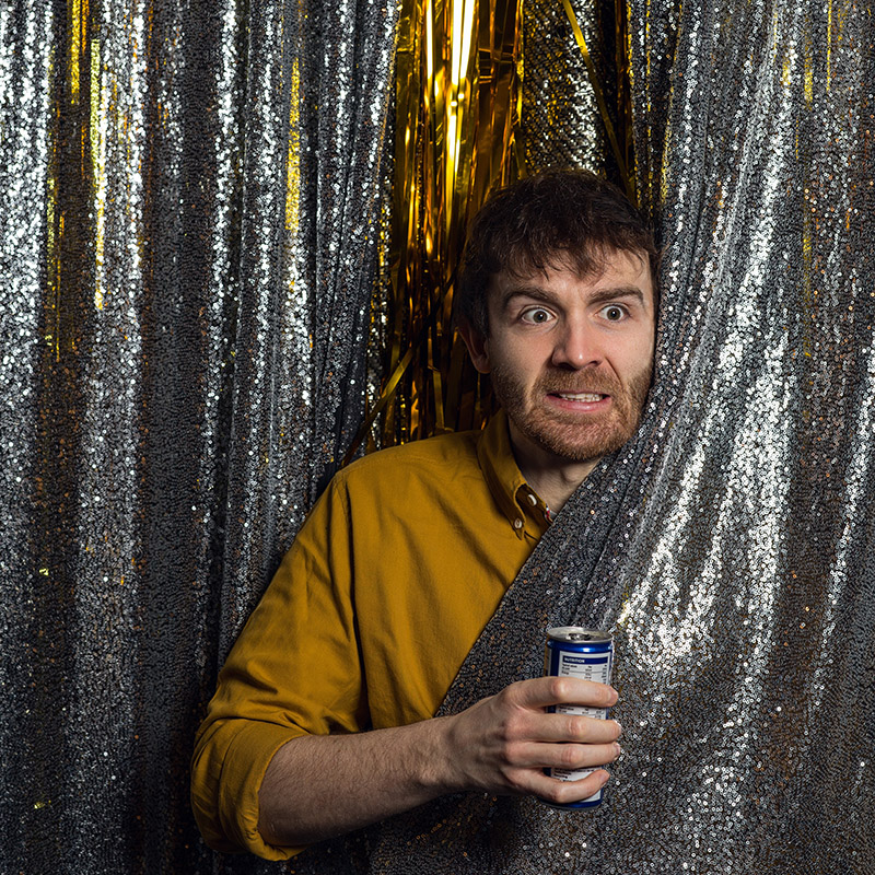 Picture of Ian Smith emerging from behind a glitter curtain with a can in his hand