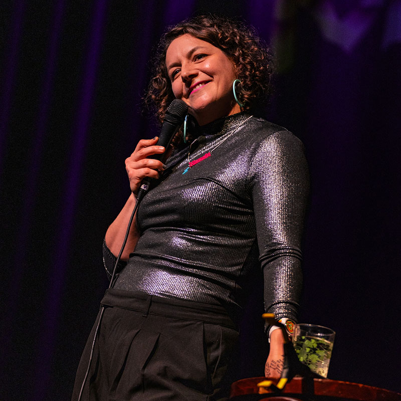 Photo of Jessica Fostekew on stage holding a microphone