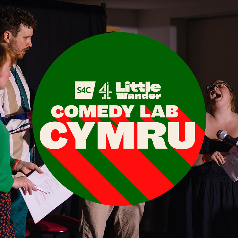 Comedy Lab Cymru logo over the top of a photo of a comedy lab show from last year