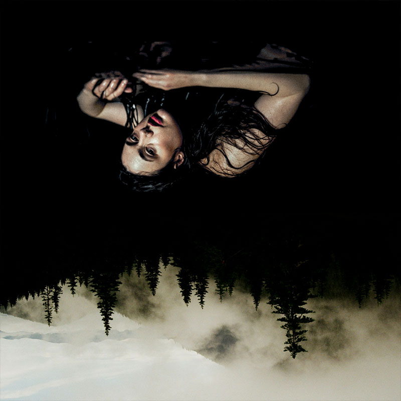 Upside down moody photo of Marjolein lying at the foot of a silhouette of a trees scattered on a mountain