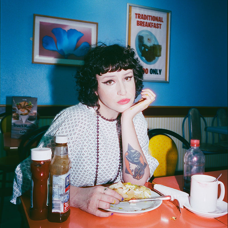 Picture of Molly McGuinness sat at a table in a cafe looking serious