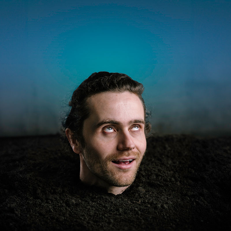 Photo of Tom Lawrinson buried up to his neck in soil and smiling