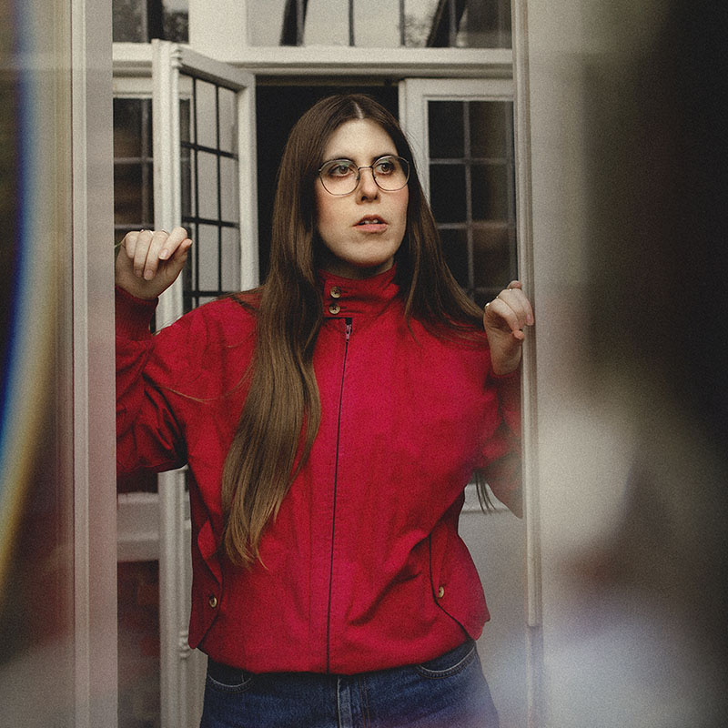 Photo of Ele McKenzie stood in the middle of a doorway, looking into the distance