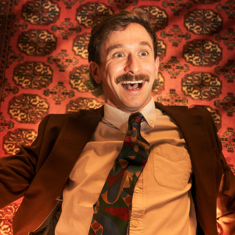 Photo of Rob Copland smiling, dressed in a shirt, tie and jacket